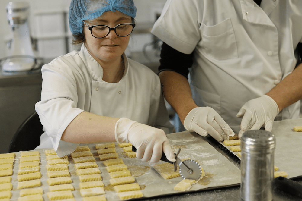 Une travailleuse en situation de handicap découpe la pâte pour former des biscuits
