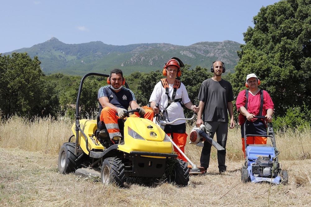 Le groupe des travailleurs espaces verts pose pour la photo avec tout leur matériel : tondeuse, tracteur tondeuse, rotophile et souffleuse.