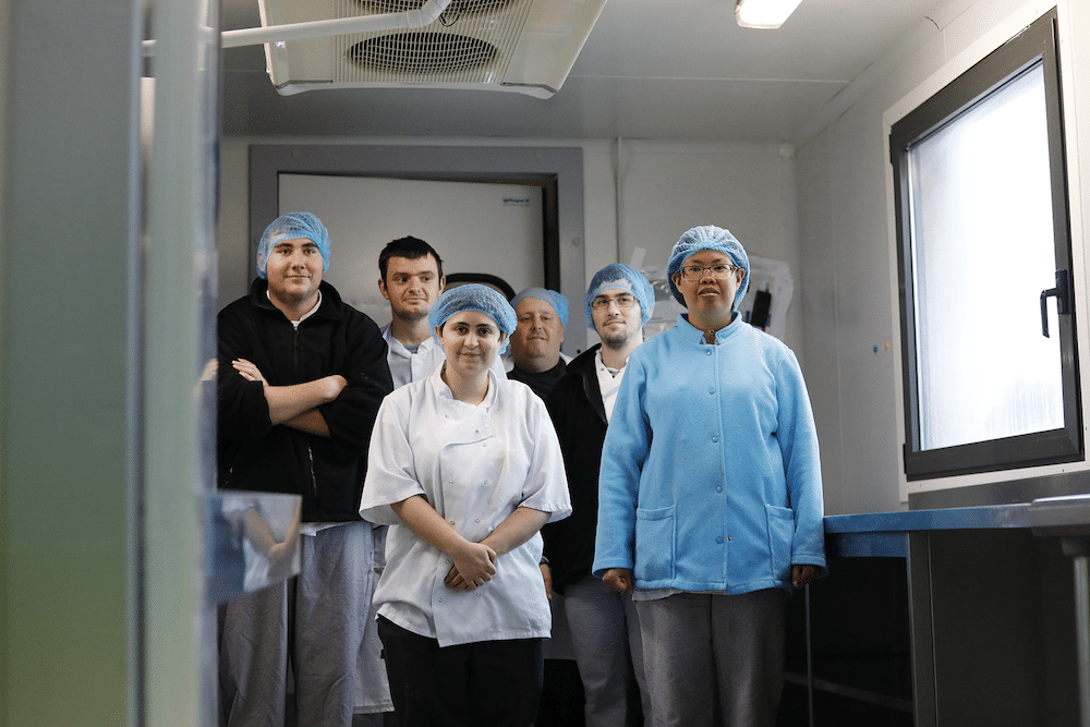 Un groupe de travailleurs en pâtisserie pose pour la photo en tenue professionnelle.